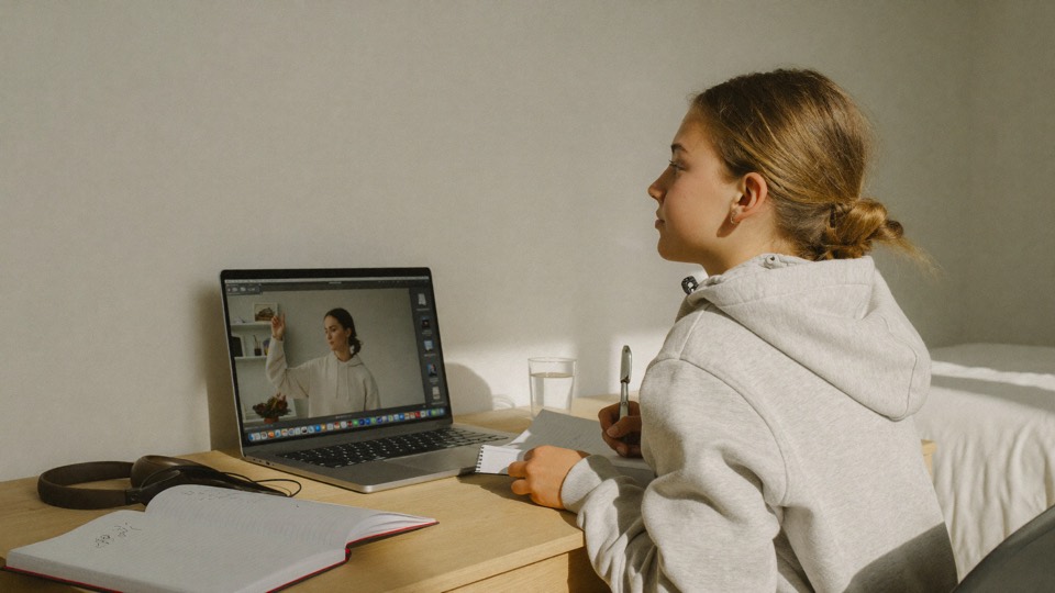 En elev följer ett studiepass på laptopen hemma vid skrivbordet.